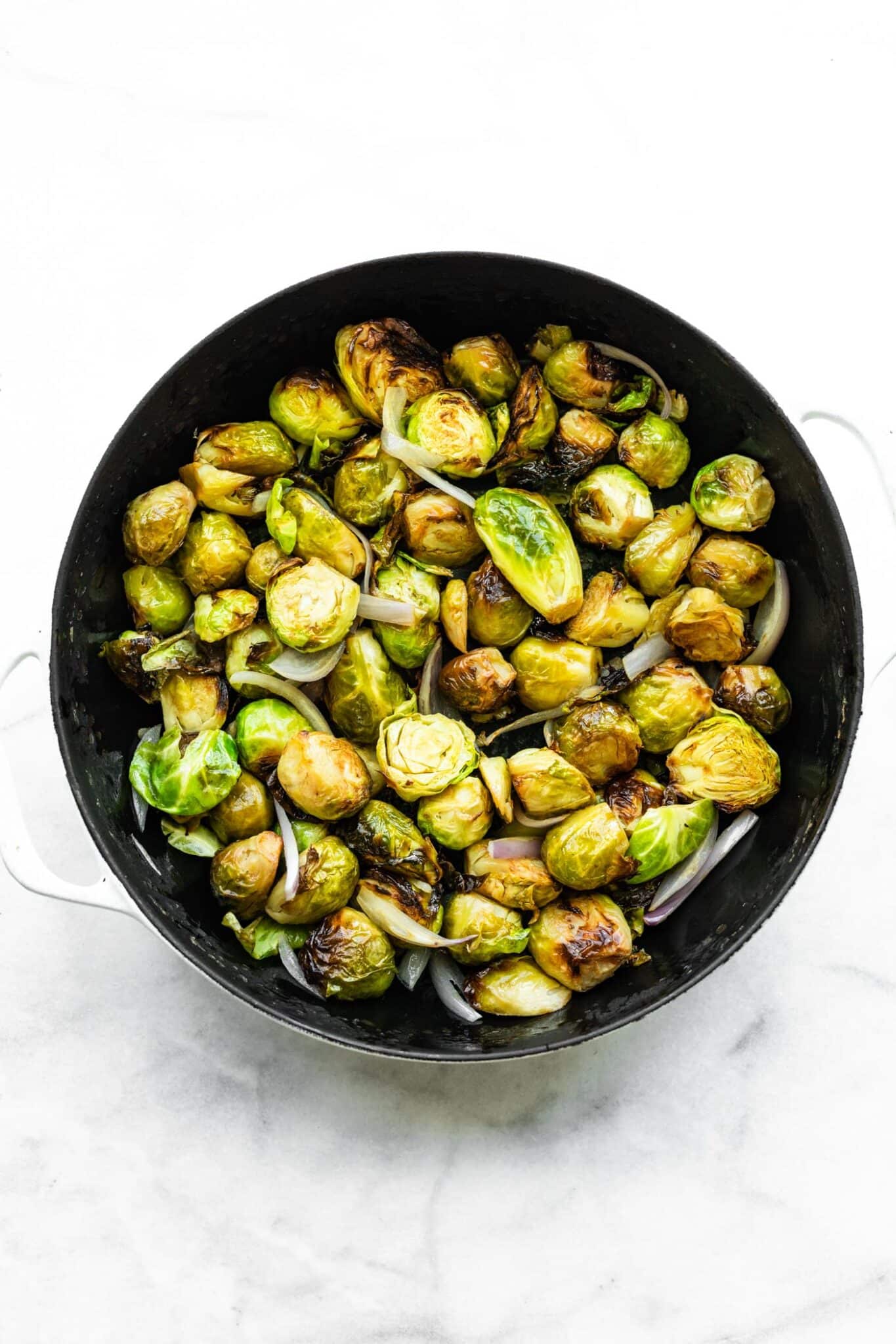 Roasted brussel sprouts with onion in a cast iron pan.