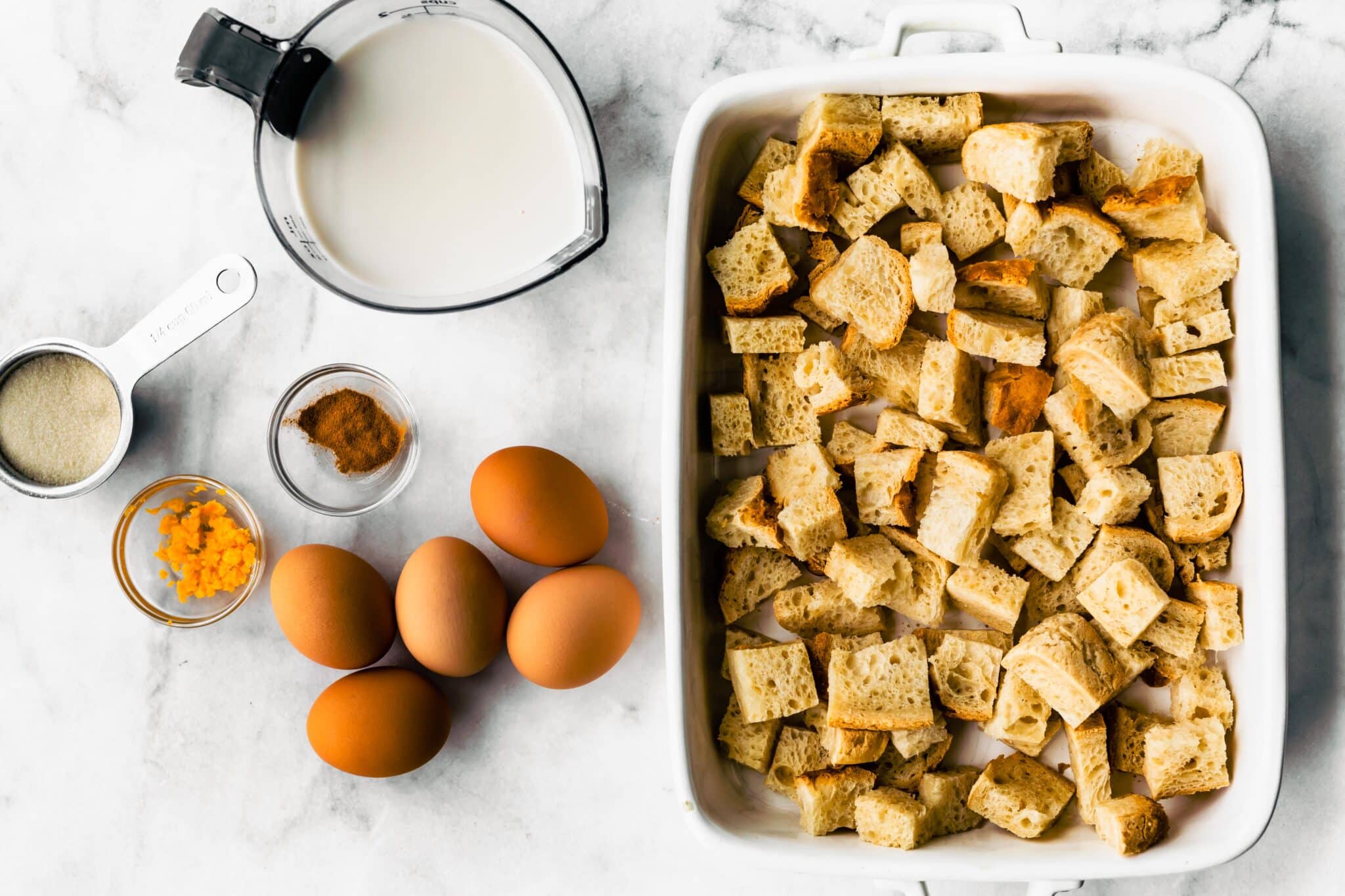 Ingredients for gluten free French toast casserole on a white marble countertop.