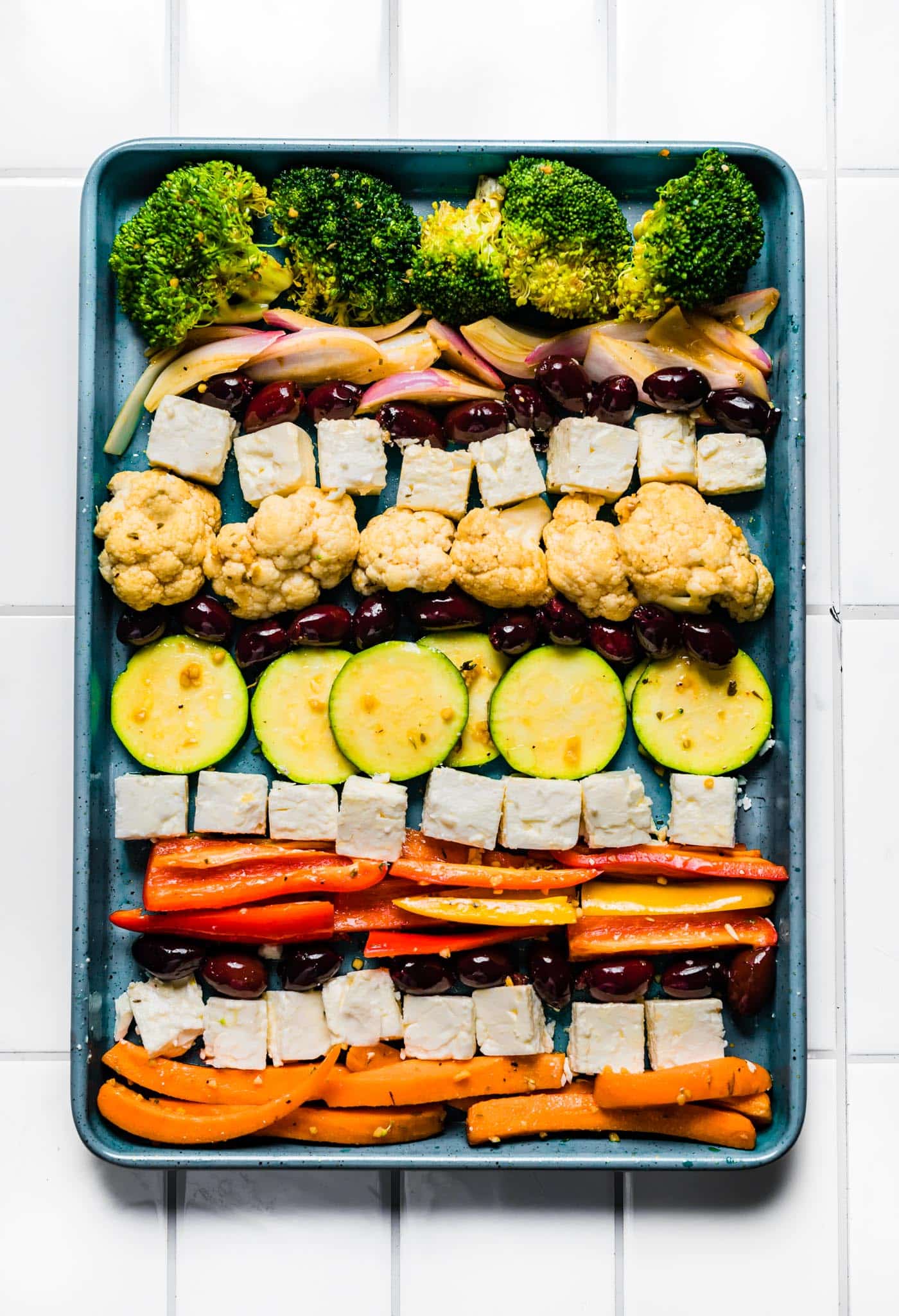 Marinated vegetables neatly arranged in rows on a sheet pan.