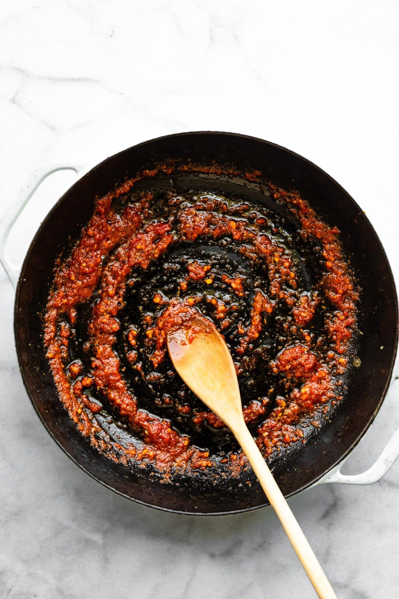 Stirring tomato paste into sauteed garlic and melted anchovies.