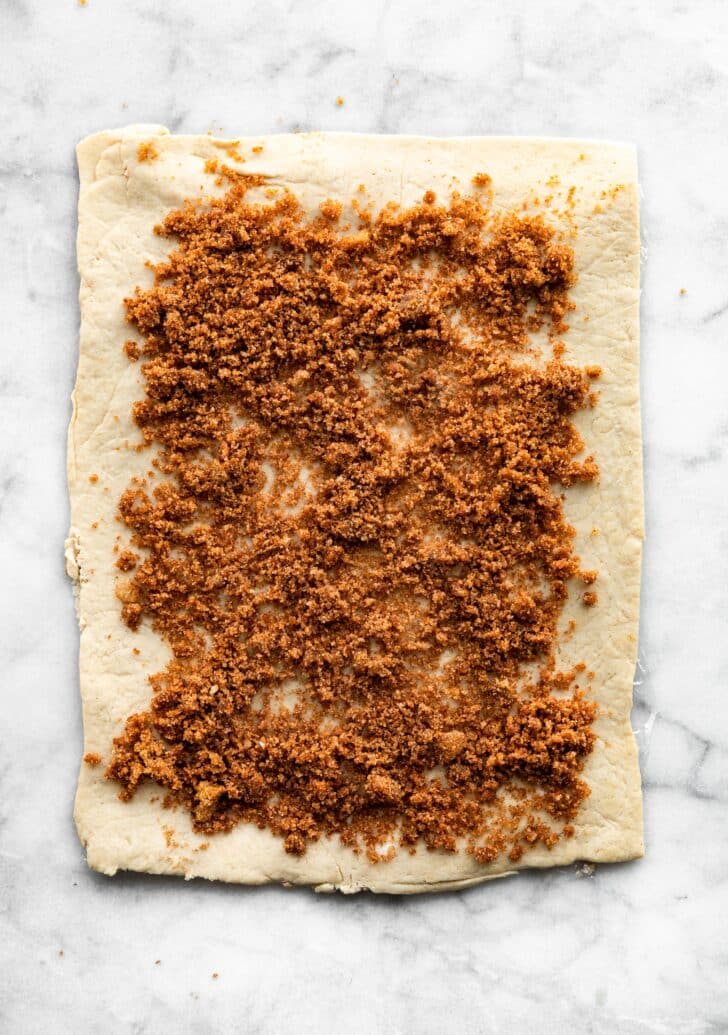 gluten free cinnamon roll dough rolled out with filling in spread over it