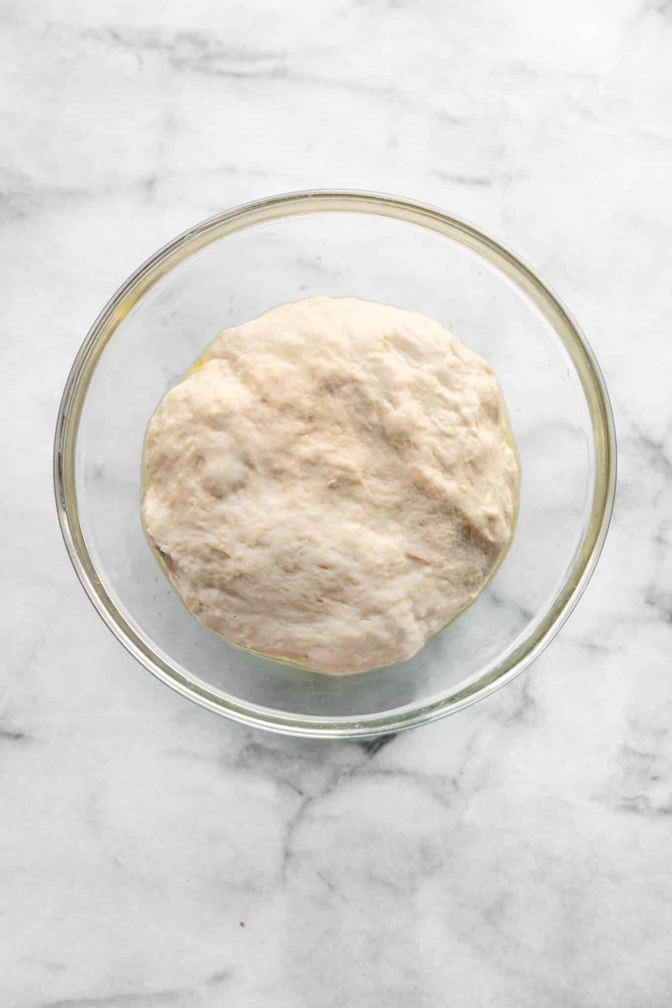Gluten free pizza dough in a glass bowl.