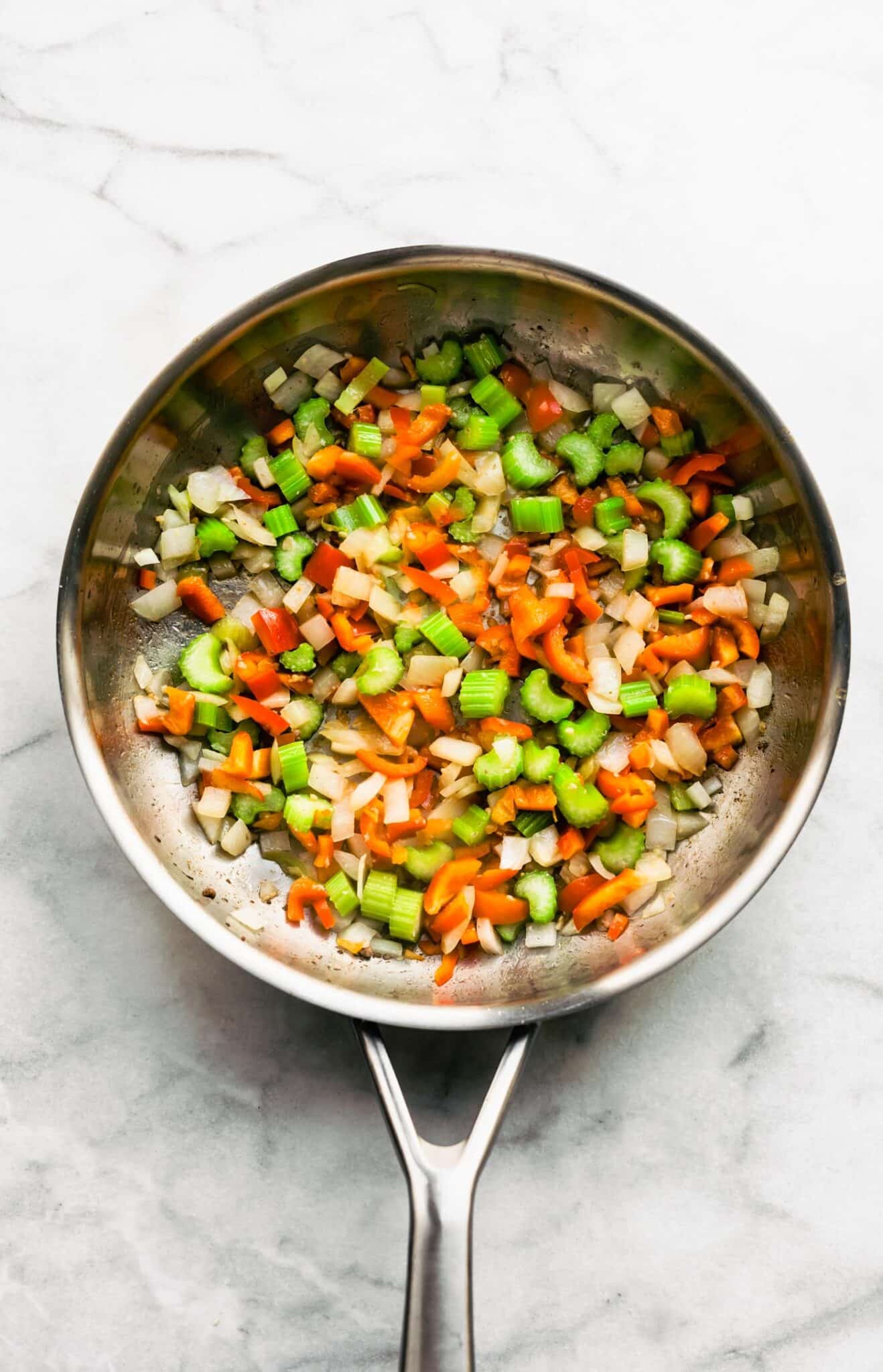 A metal saute pan with sauteed veggies.