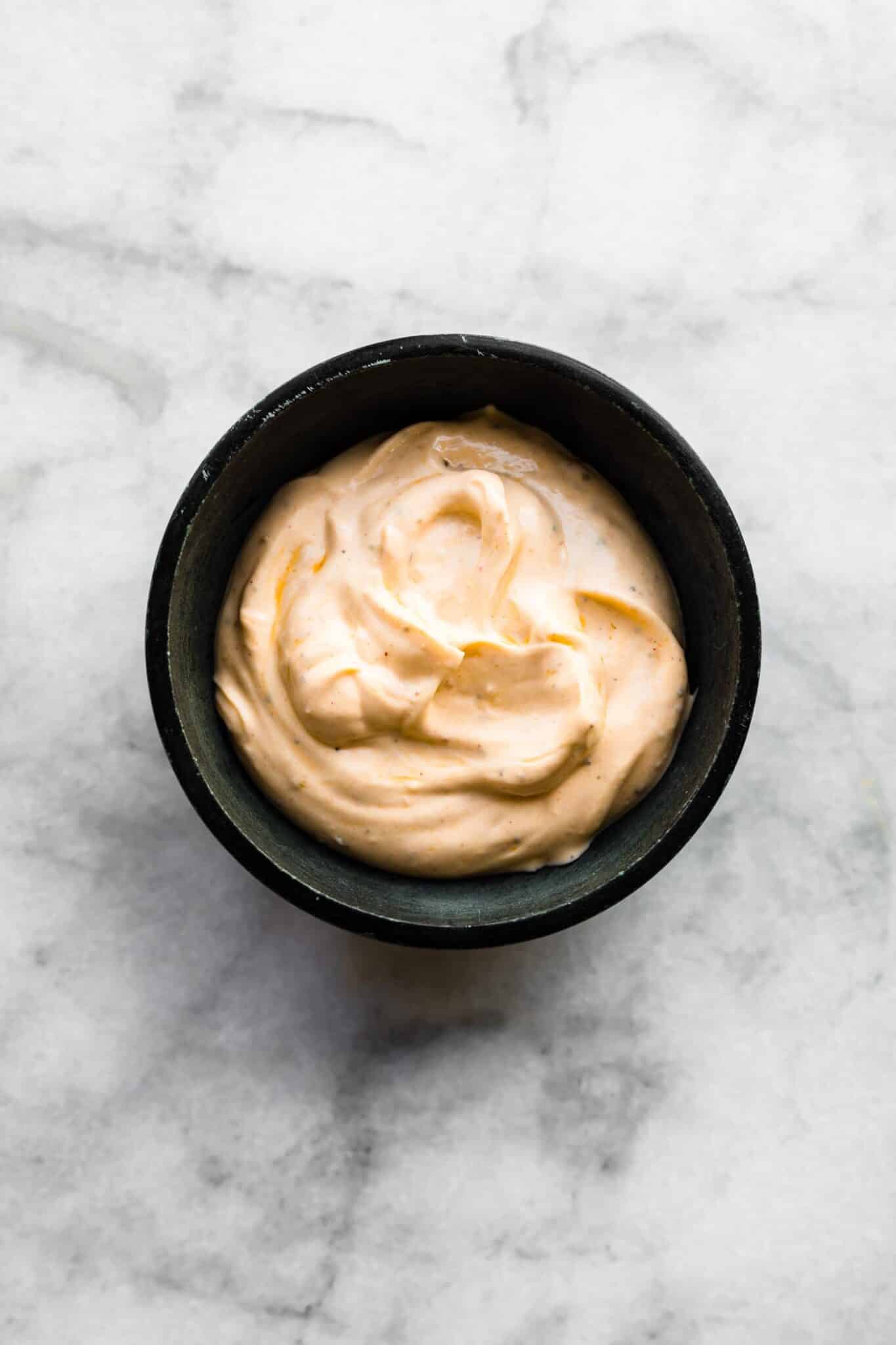 A small black bowl of paprika yogurt sauce.