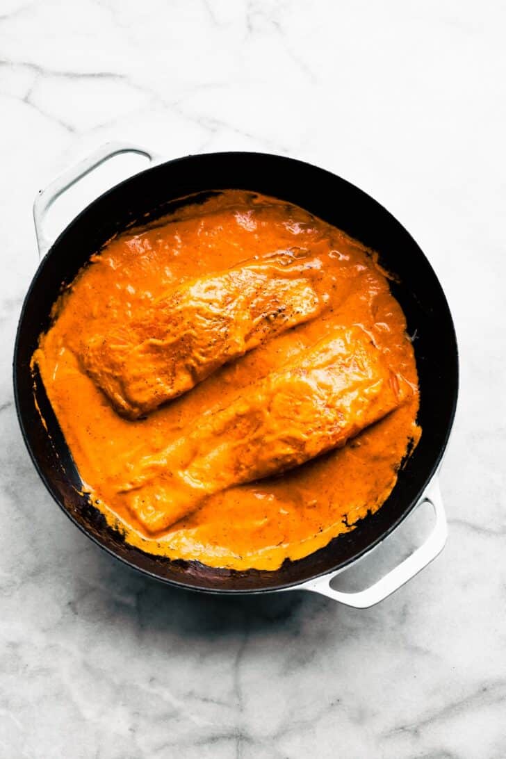 pan of seared salmon covered in red pepper sauce