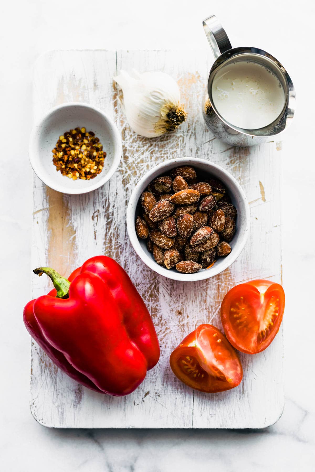 ingredients to make roasted red pepper sauce on white wooden cutting board