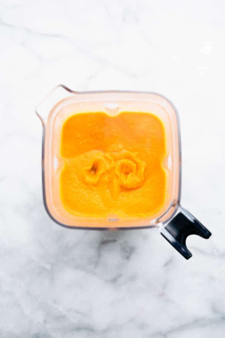 an overhead image of blended root vegetable soup in a blender