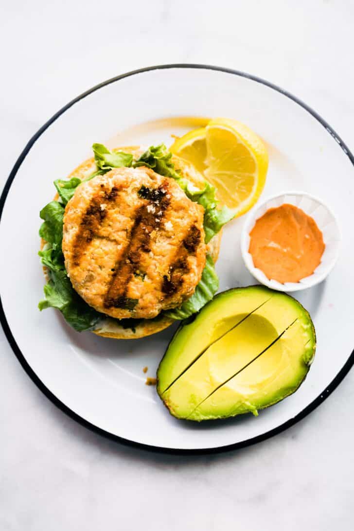 Overhead photo of an open faced salmon burger on lettuce and a gluten free bun.