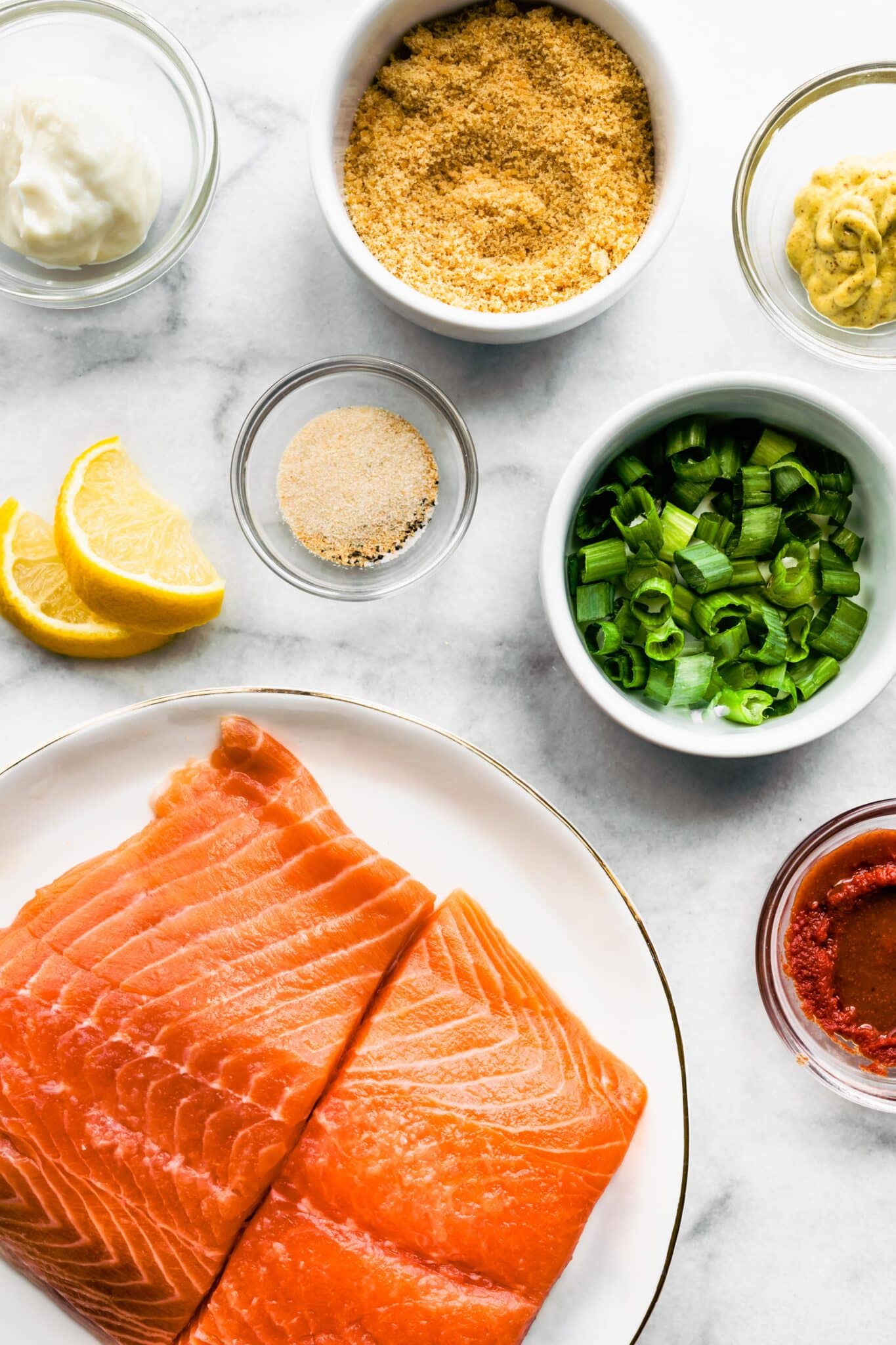 Overhead photo of raw salmon filets, green onions and panko for salmon burgers.