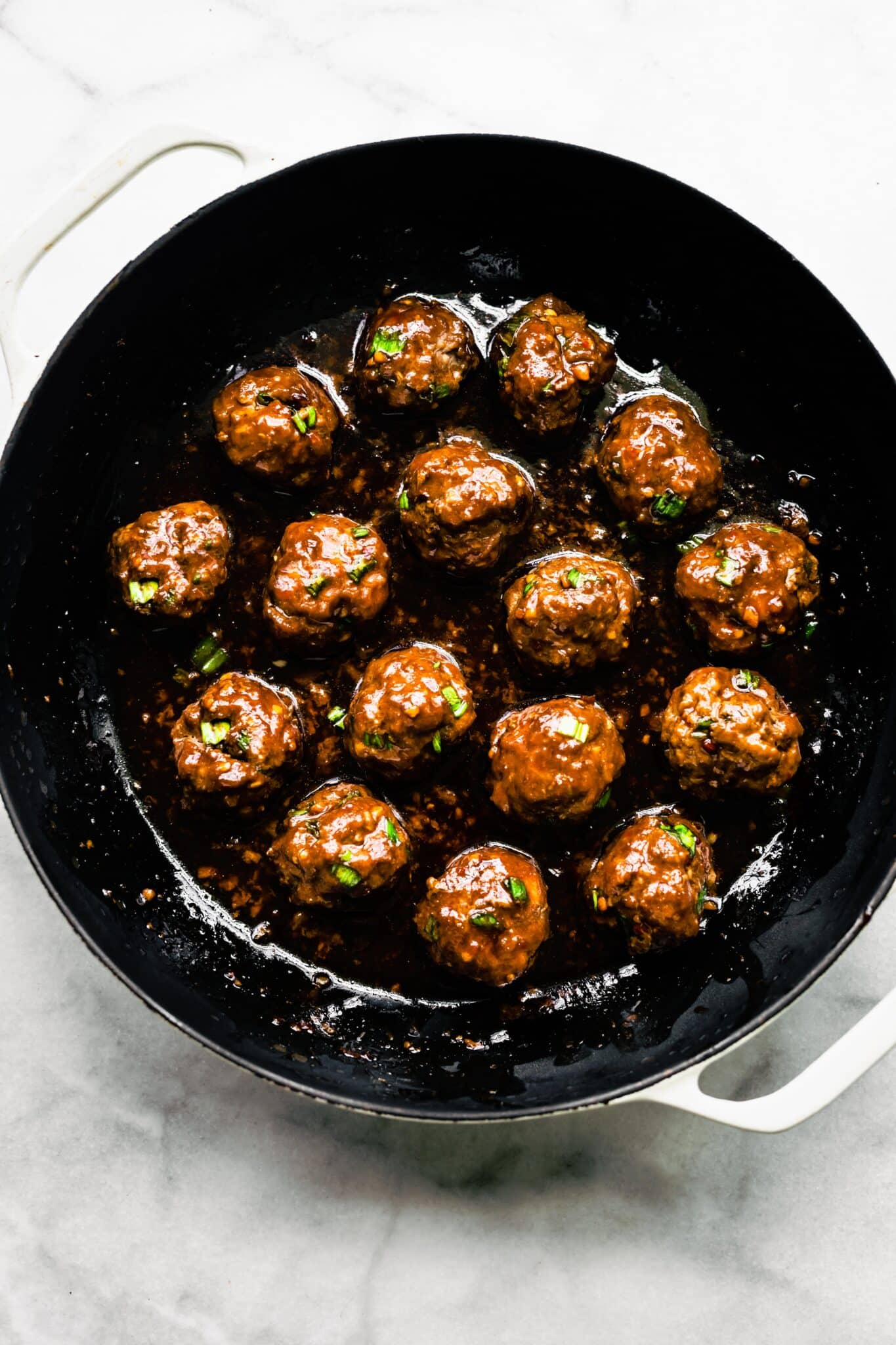 Overhead photo of saucy Asian meatballs in a cast iron pan.