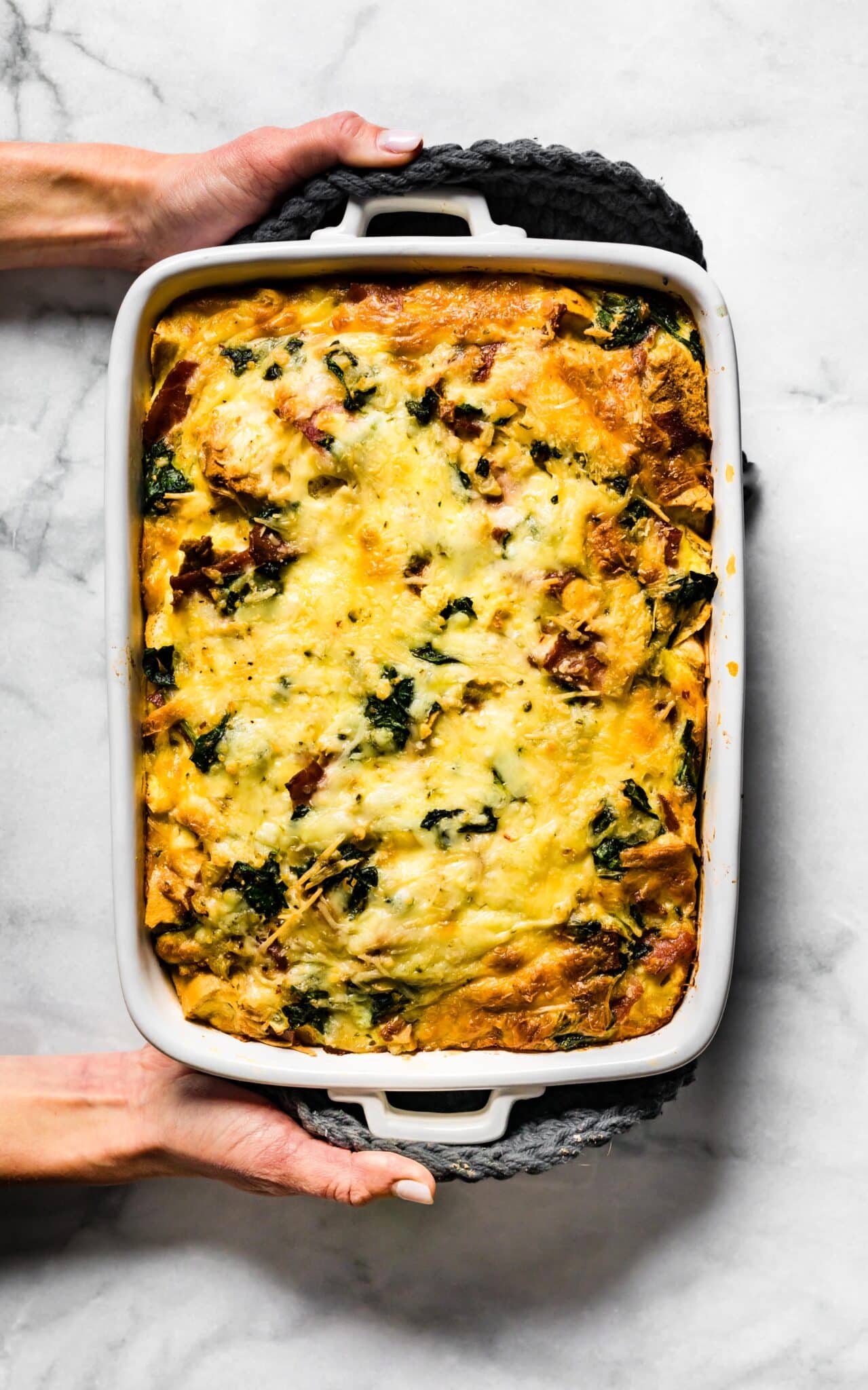 Overhead photo of a woman's hands holding a gluten free breakfast strata.