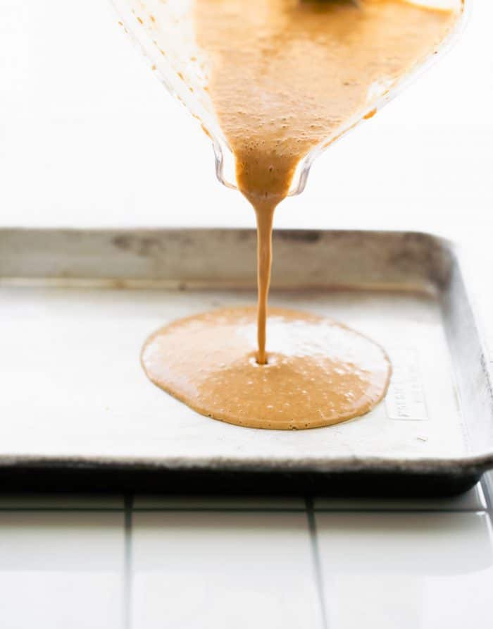 pouring protein pancake batter into a sheet pan