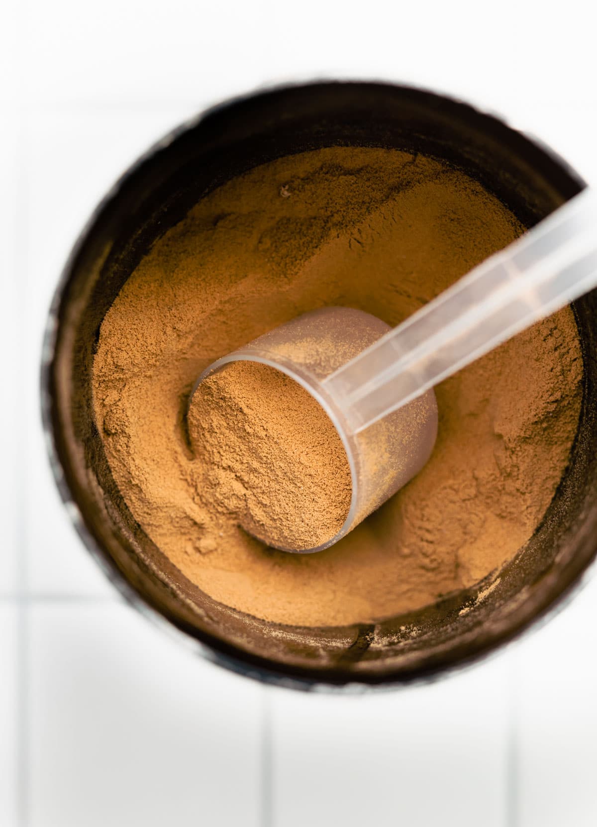 overhead image with scoop of chocolate bone broth protein in canister