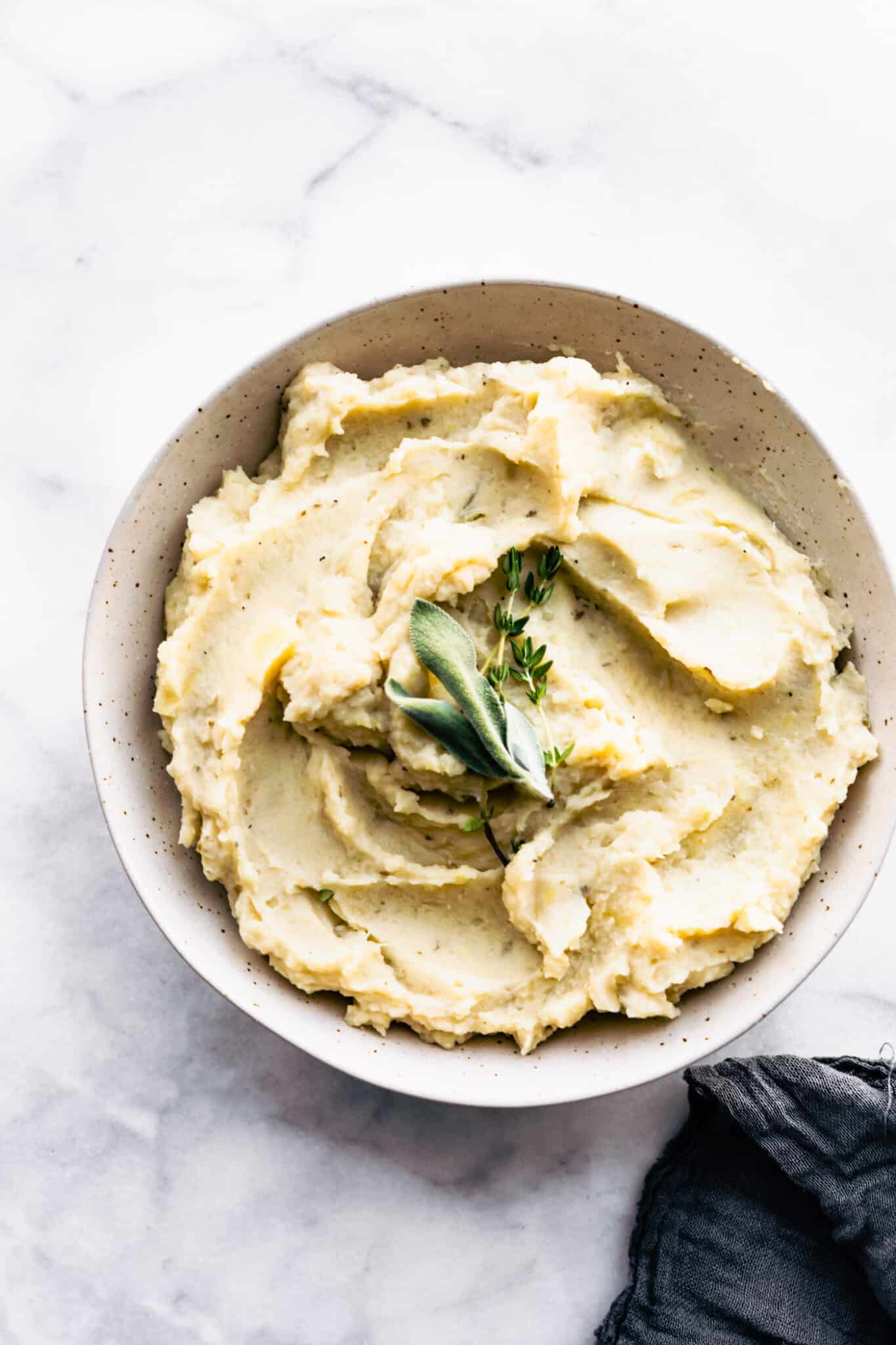 HERO SHOT - A white bowl full of slow cooker dairy free mashed potatoes topped with fresh herbs