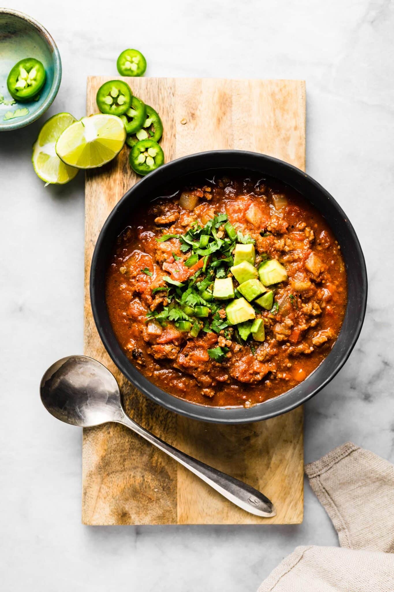 A pretty bowl of paleo chili topped with avocado and cilantro.