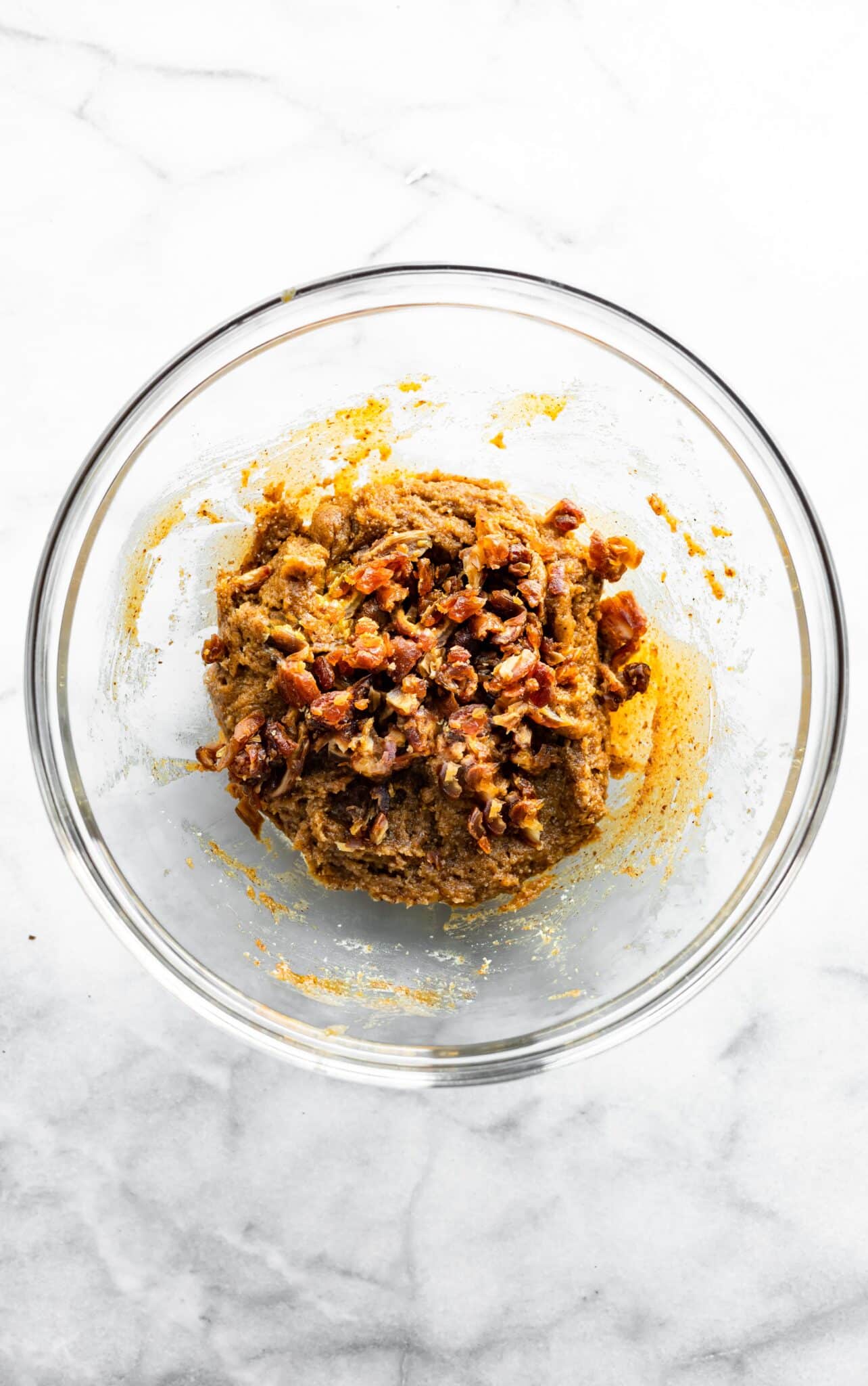 Pieces of dates on top of paleo bars batter ready to be mixed.