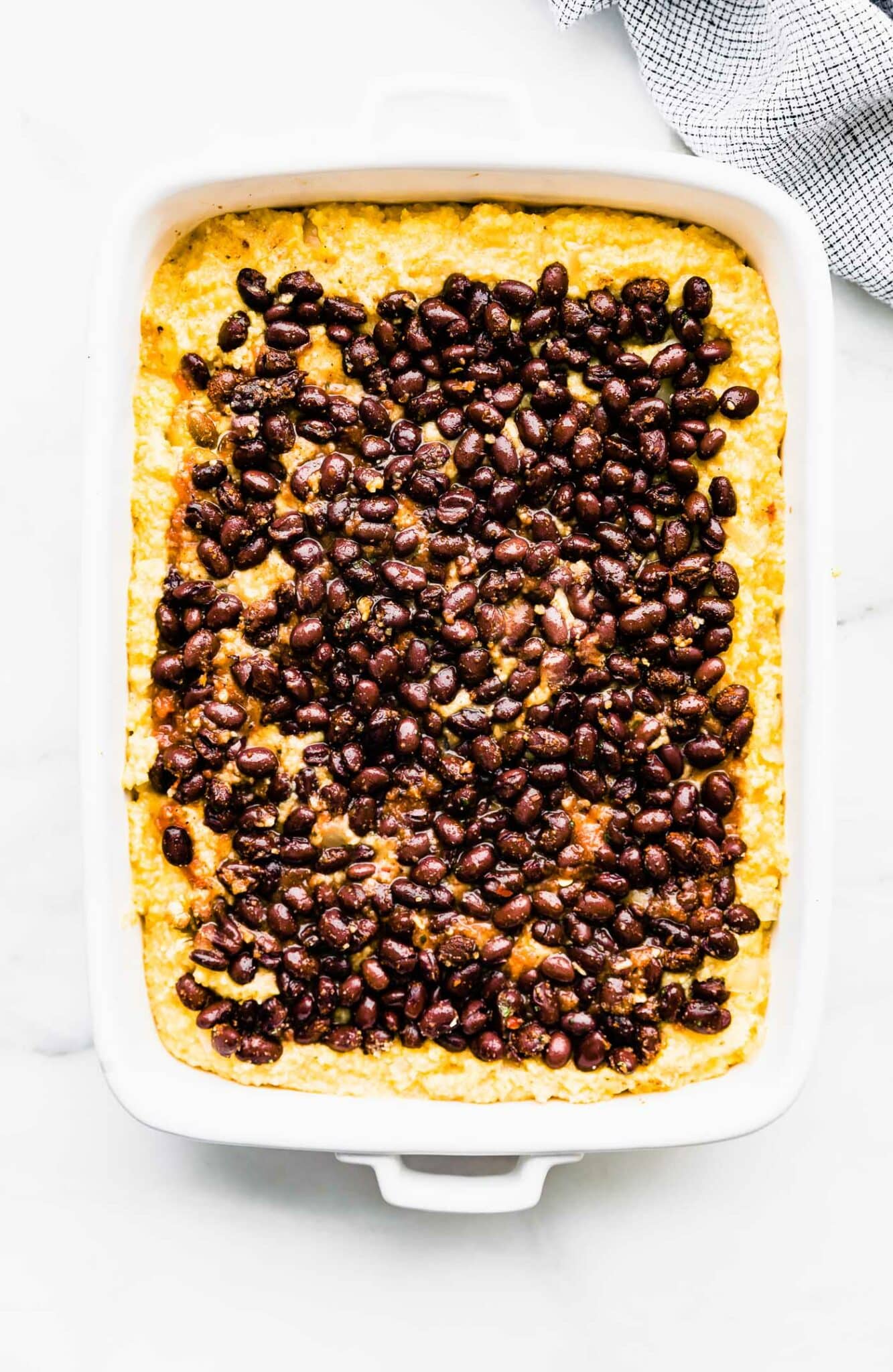 black beans over polenta in a white casserole dish