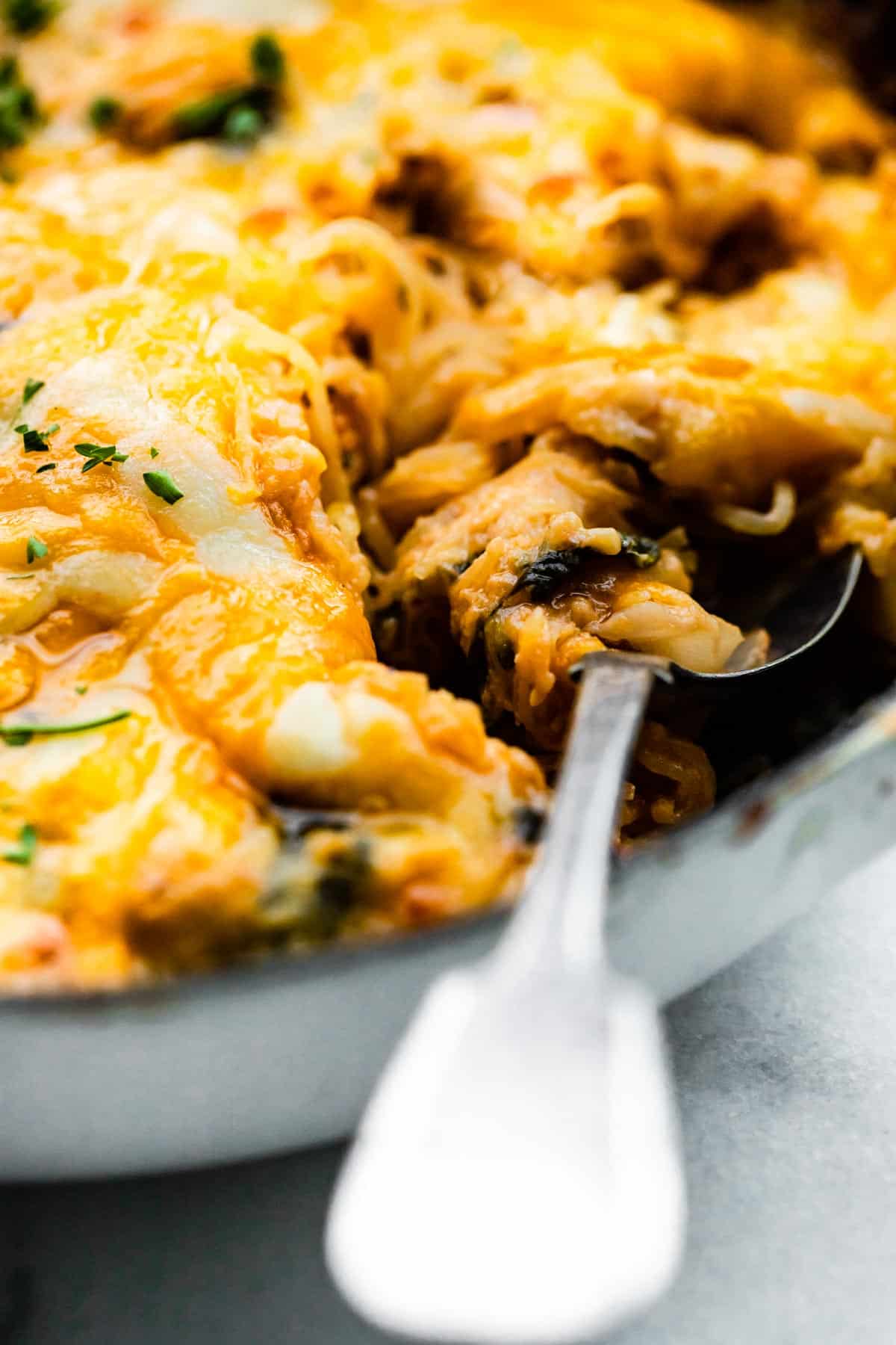 Up close photo of a spoon digging into a cheesy spaghetti squash casserole.