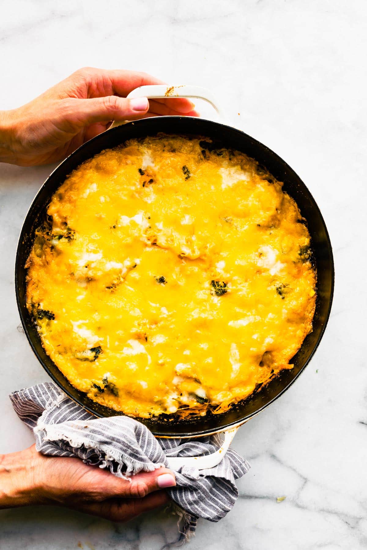 Overhead photo of two woman's hands holding a gluten free spaghetti squash casserole.