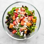 Crumbled feta cheese on a bed of mixed greens, roasted rhubarb, and strawberries.
