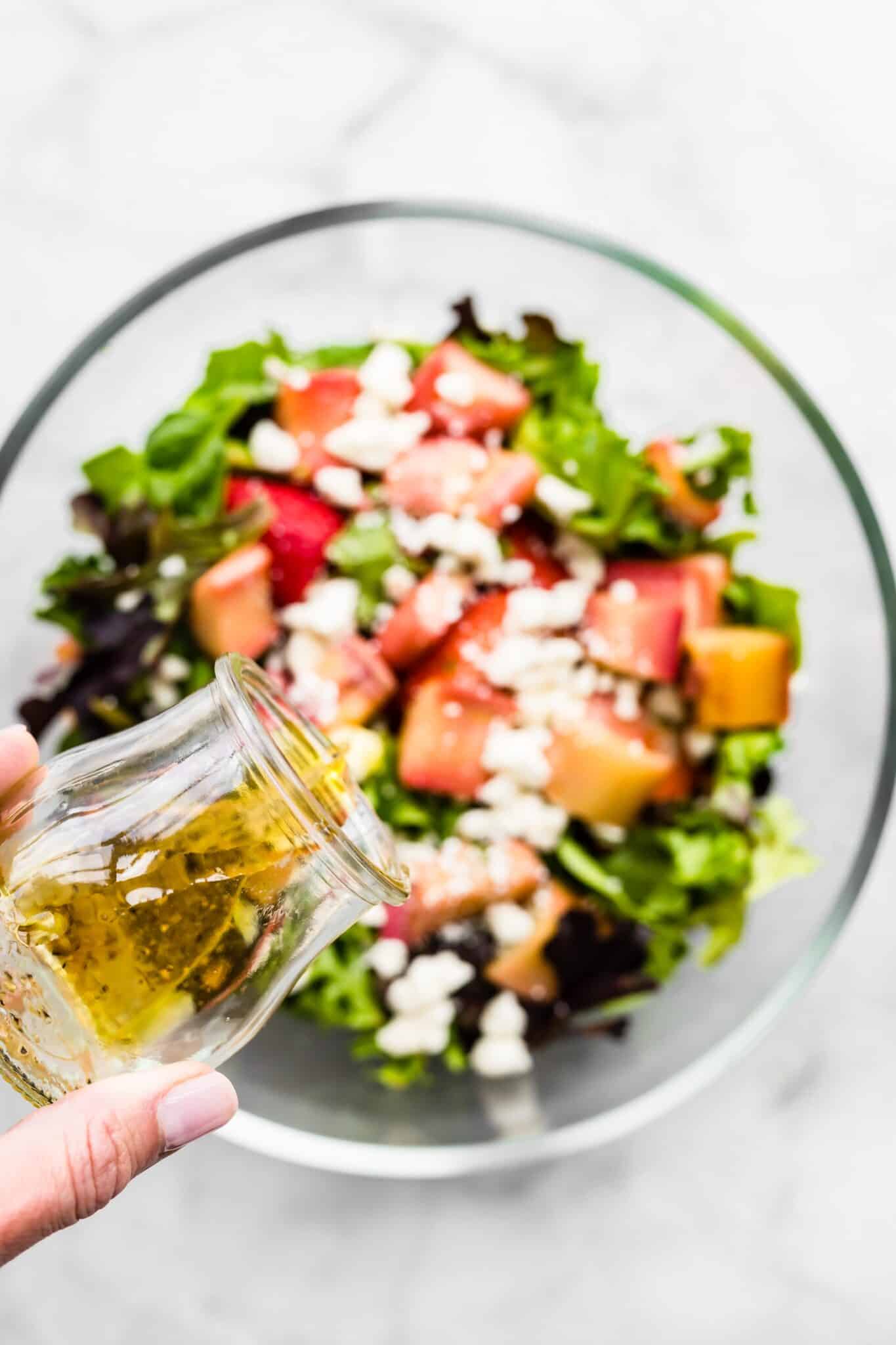 A vinaigrette dressing being poured on to a roasted rhubarb salad.