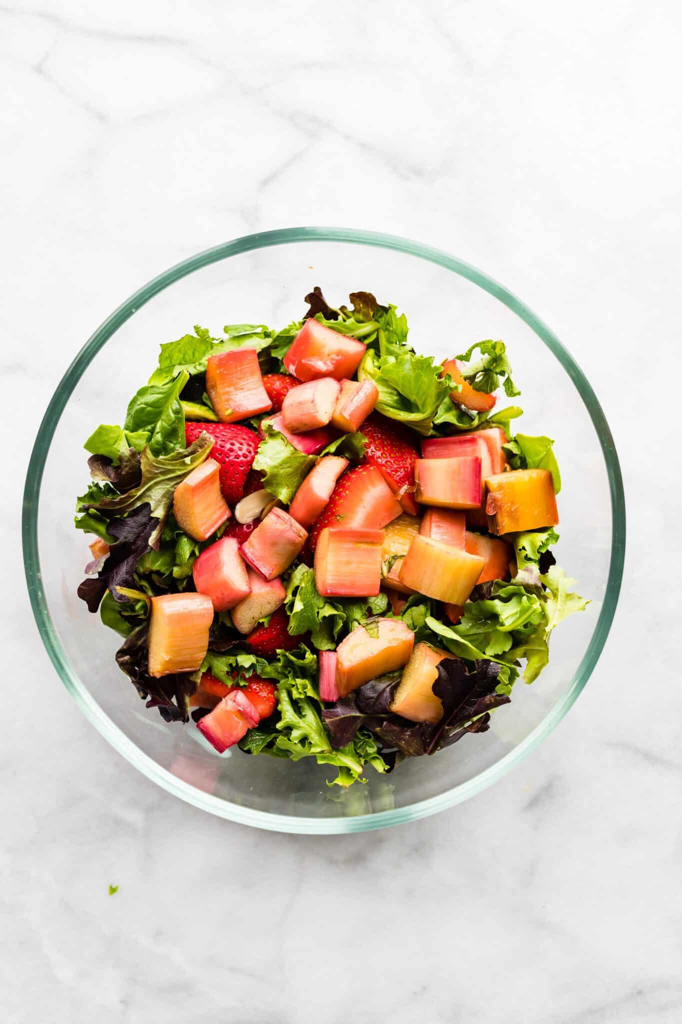 Overhead photo of sliced strawberries and roasted rhubarb on mixed greens.