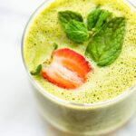 Overhead image of a blended kale and berry smoothie topped with fresh strawberry and mint leaves