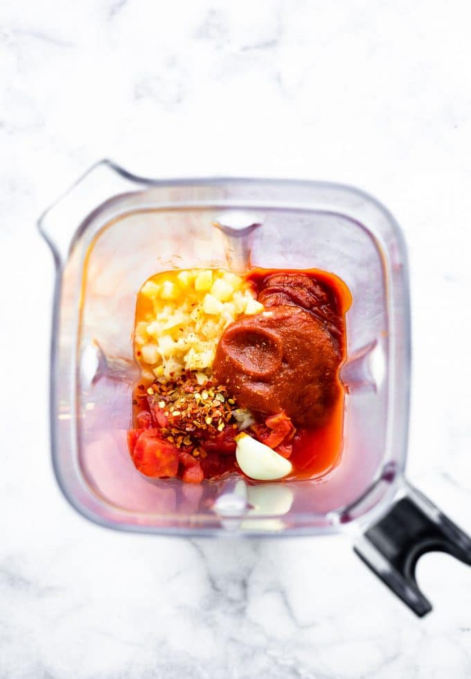 Overhead image of ingredients for meatball sauce in a blender.