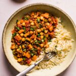 Vegetarian sweet potato picadillo and rice in a ceramic bowl with a fork.