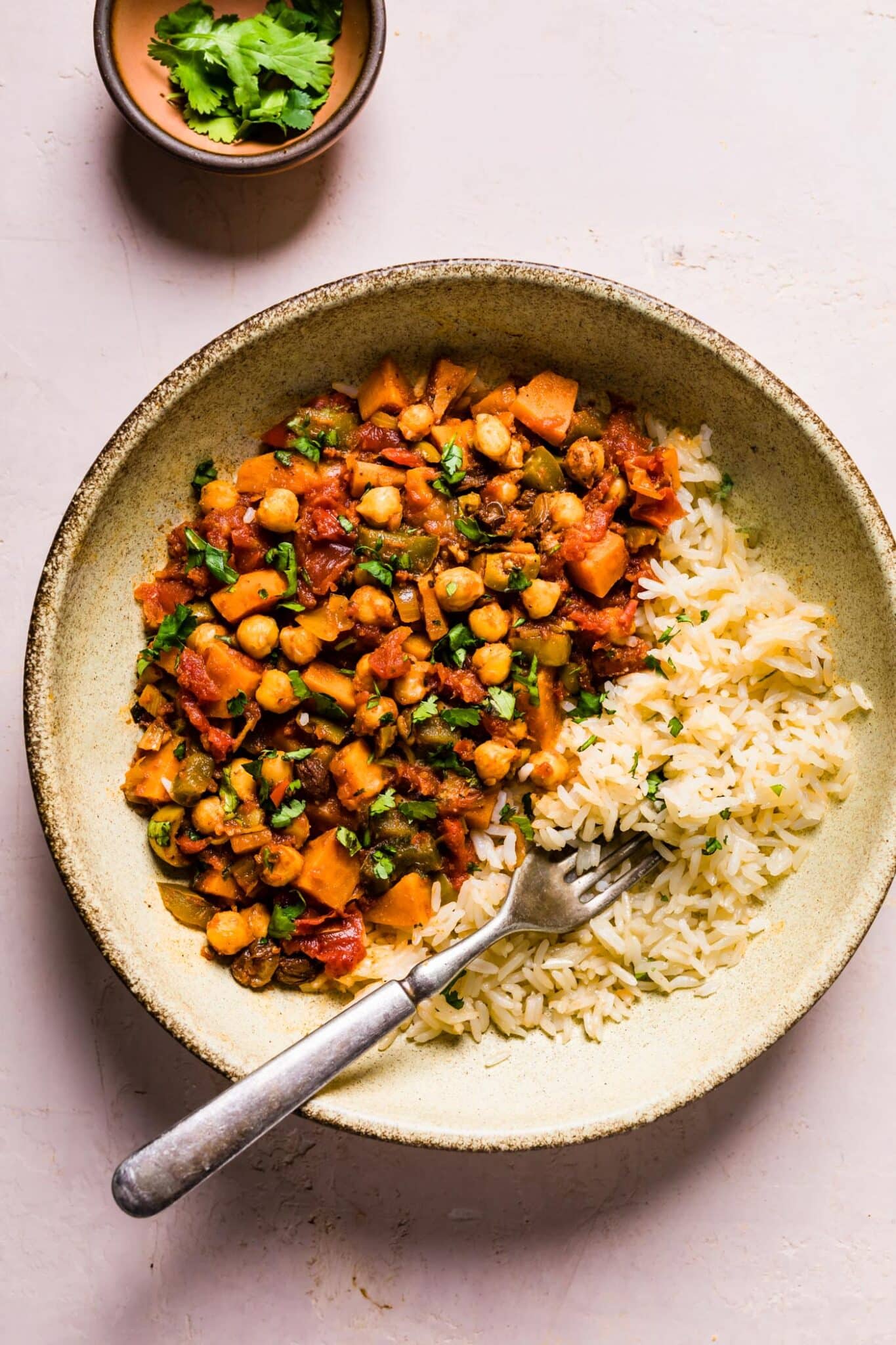 Vegetarian sweet potato picadillo and rice in a ceramic bowl with a fork.