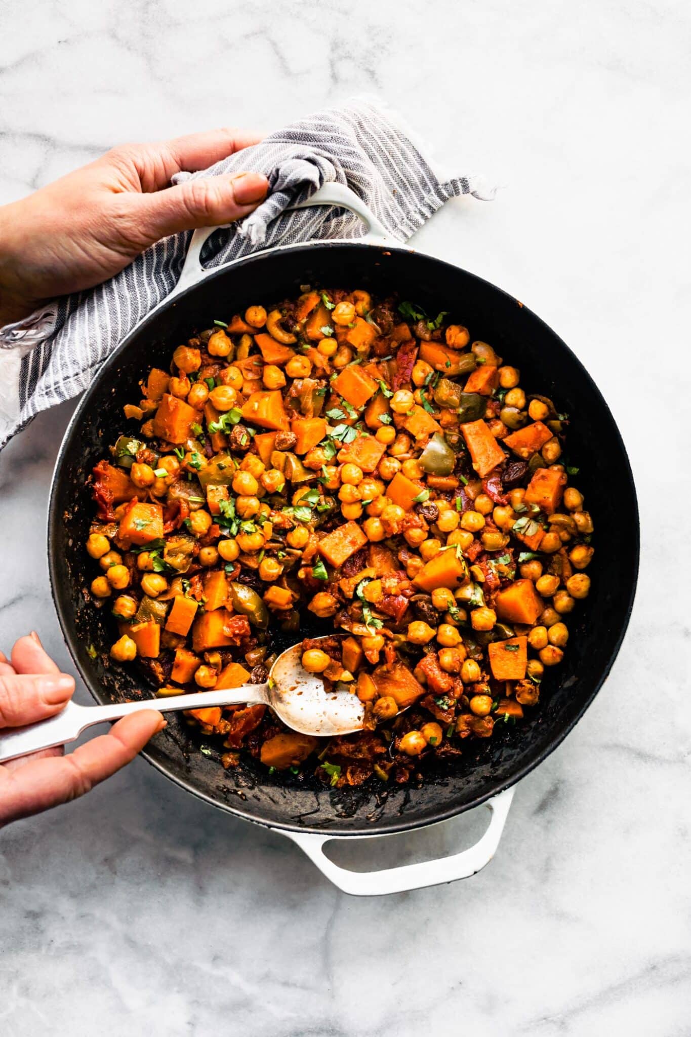 A woman using a spoon to scoop picadillo out of the pan.