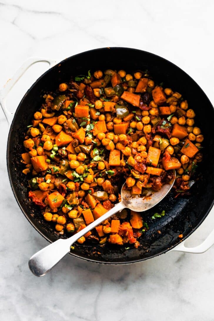Sweet potato picadillo in the pan with a portion removed with a spoon.