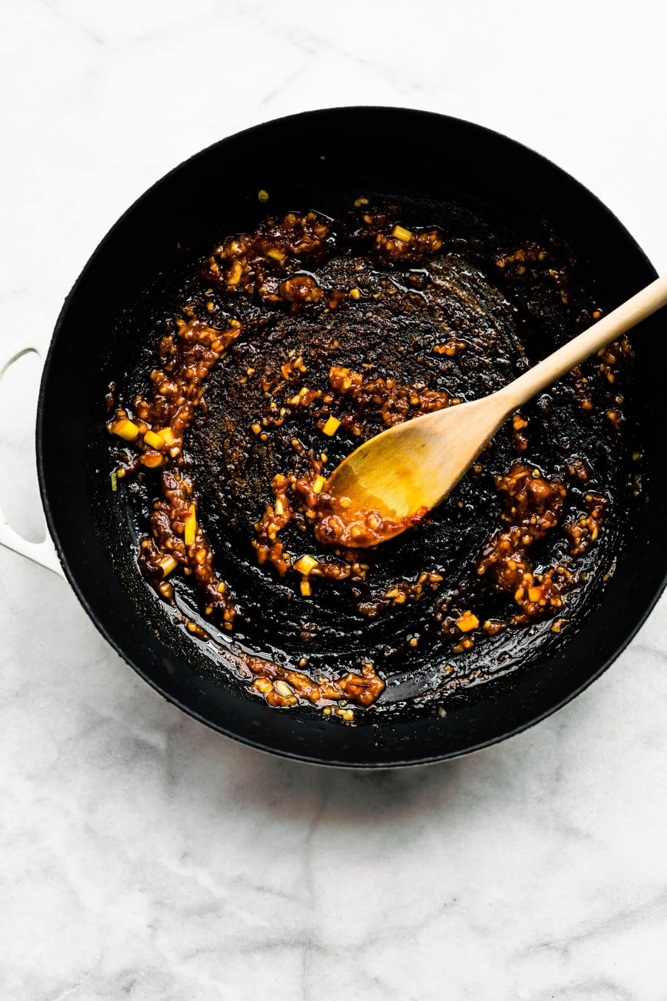 Chili paste stirred into a soup pot with sauteed garlic and ginger.