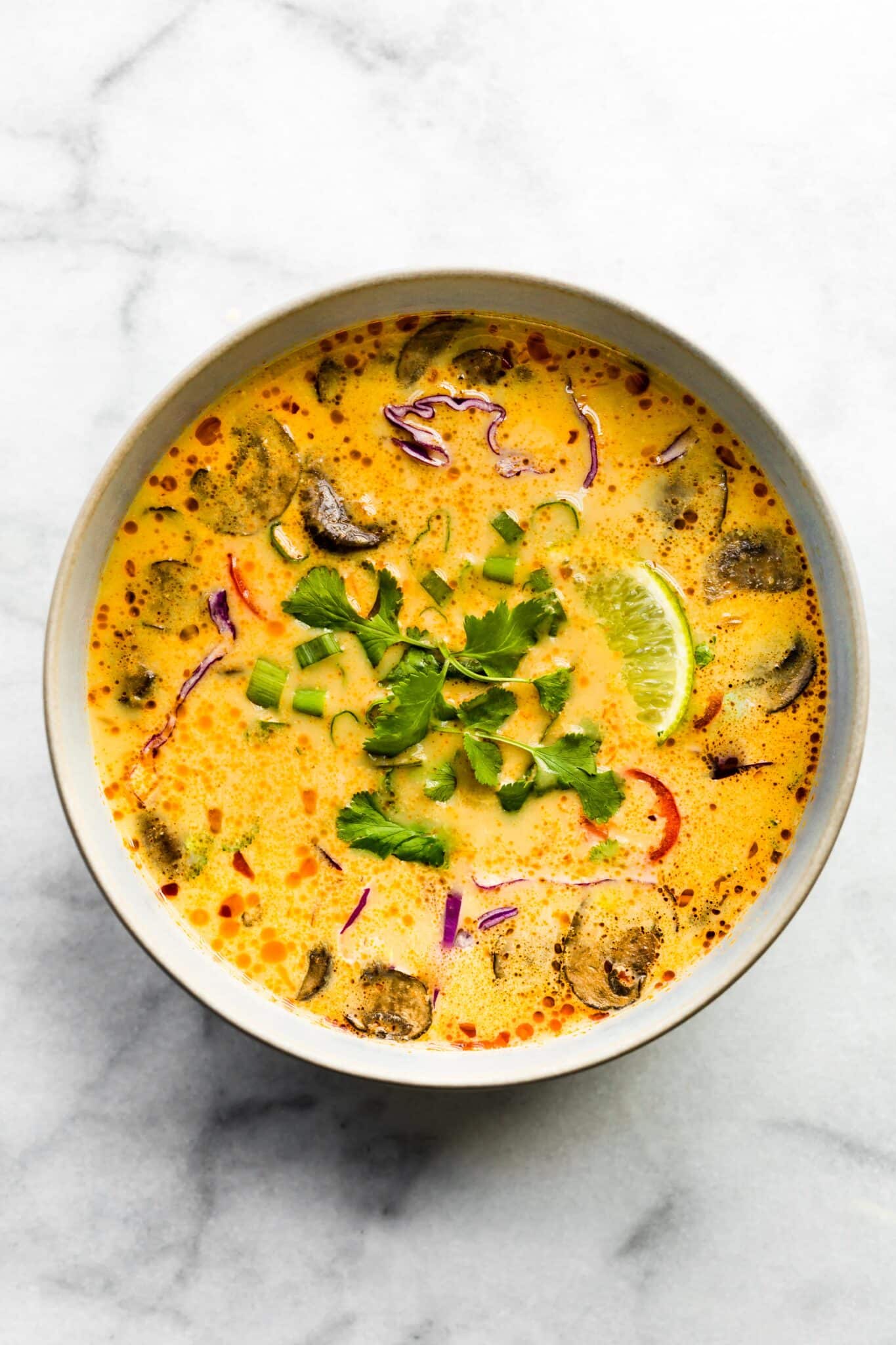 Overhead photo of Easy Thai Coconut Soup in a white bowl garnished with cilantro.