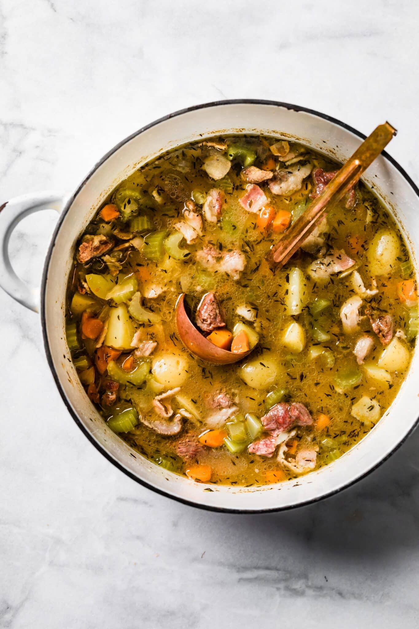 Overhead photo of Irish Lamb Stew in a white pot with a copper ladle.