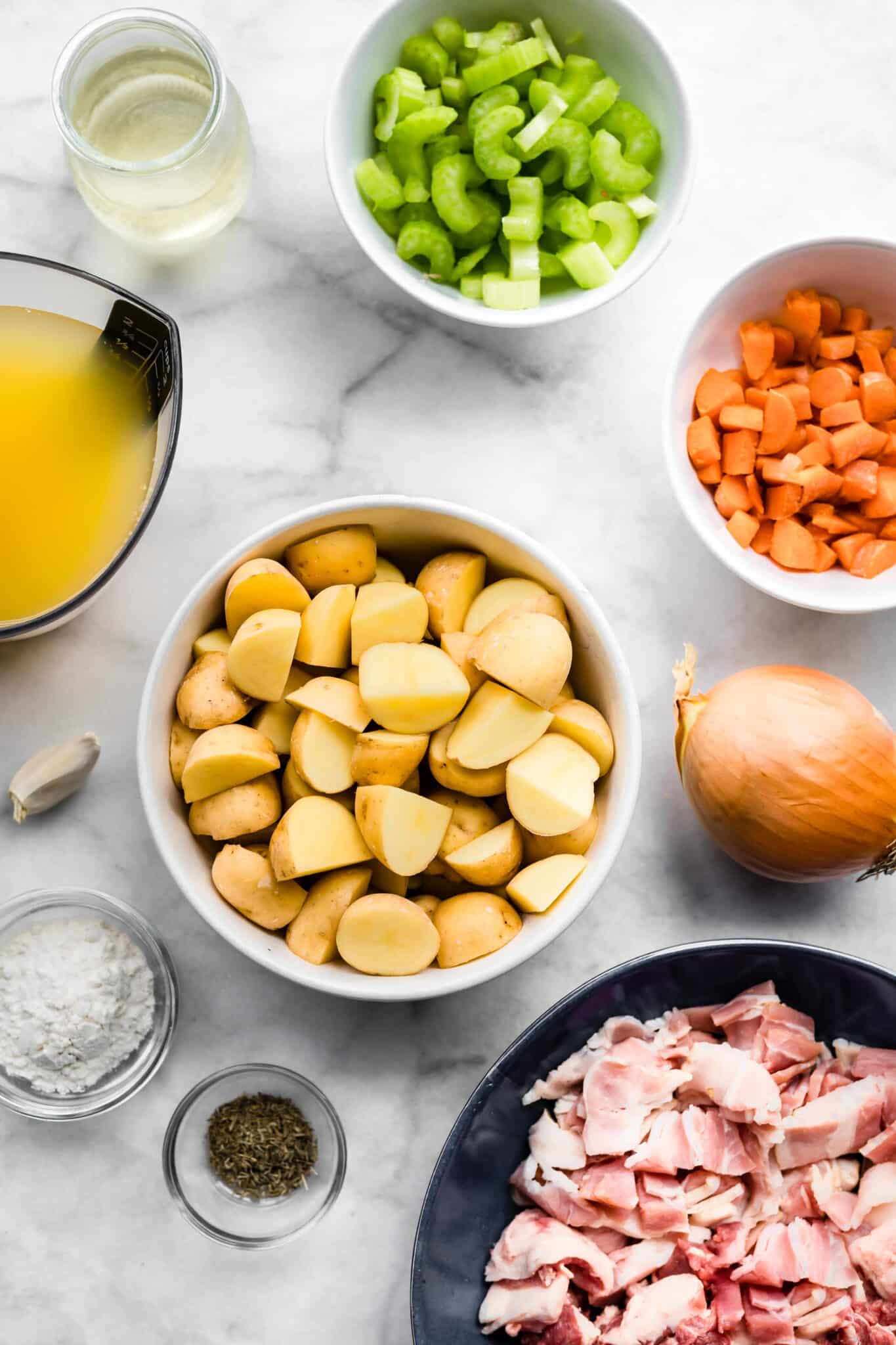 Bowls of ingredients for Irish Lamb Stew like broth, potatoes, bacon, and vegetables.