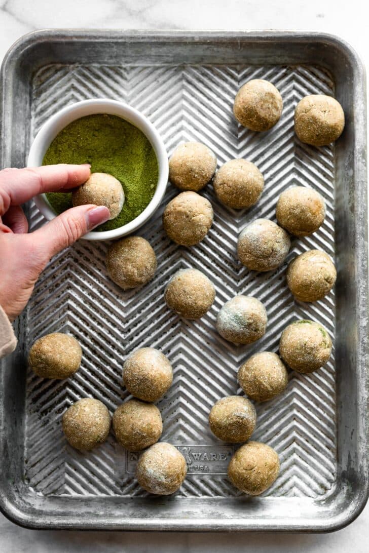 woman's hands rolling protein balls in matcha powder