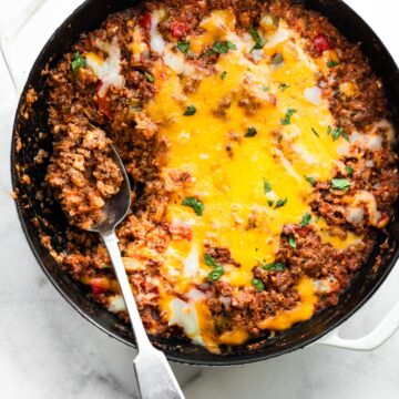 A spoon in a gluten free unstuffed bell pepper skillet topped with melted cheese.