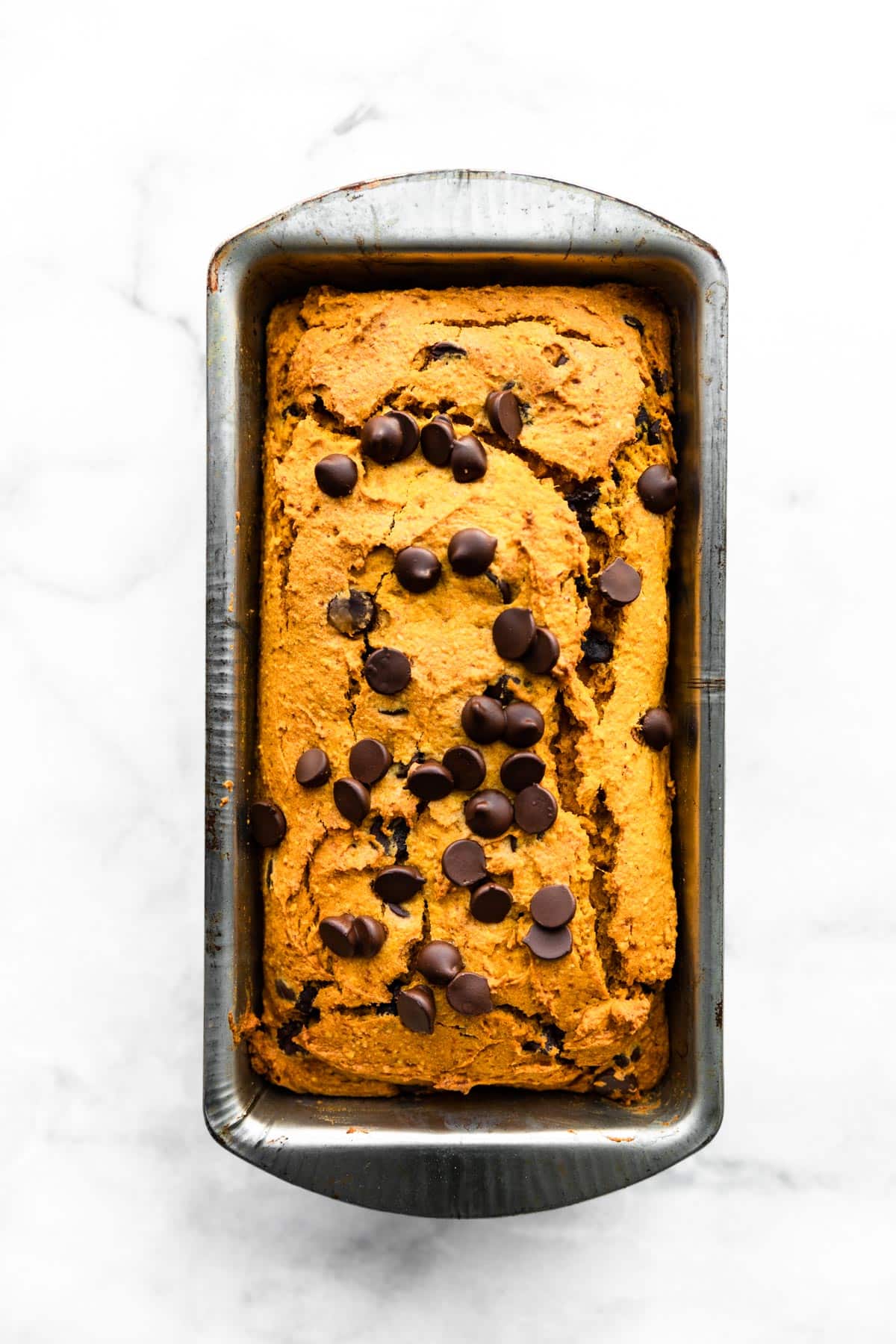 Overhead photo of vegan chocolate chip pumpkin bread in a metal bread pan.