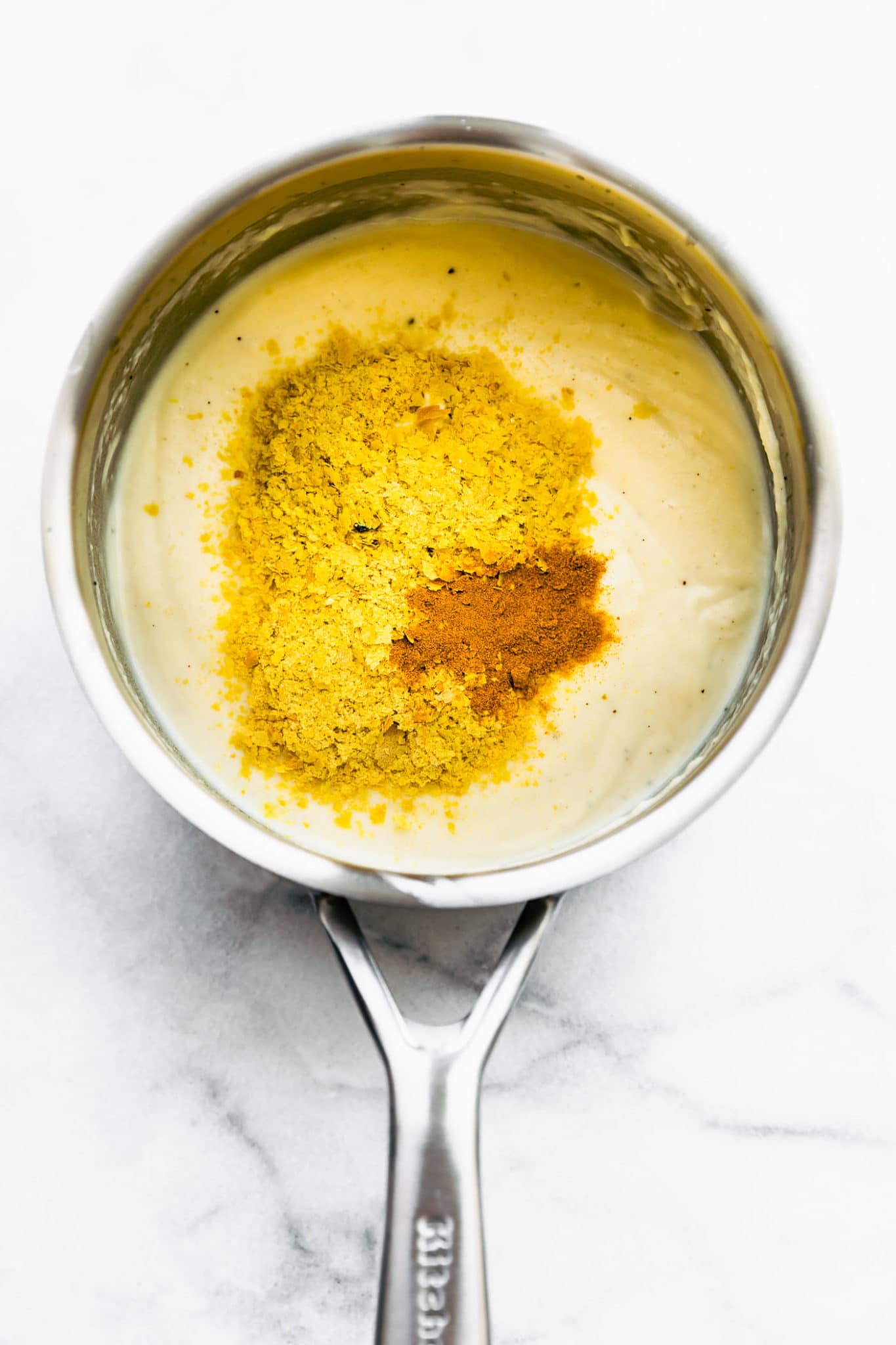 Nutritional yeast and paprika in a pan of vegan cheese sauce.