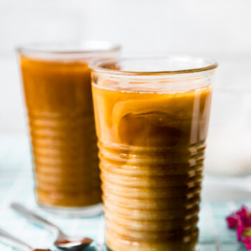 Two tall clear glasses filled with coffee latte