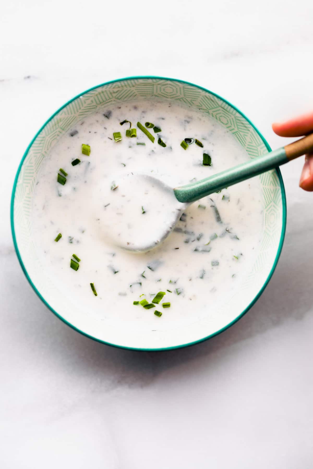 overhead: spoonful of vegan salad dressing above small green bowl filled with more dressing