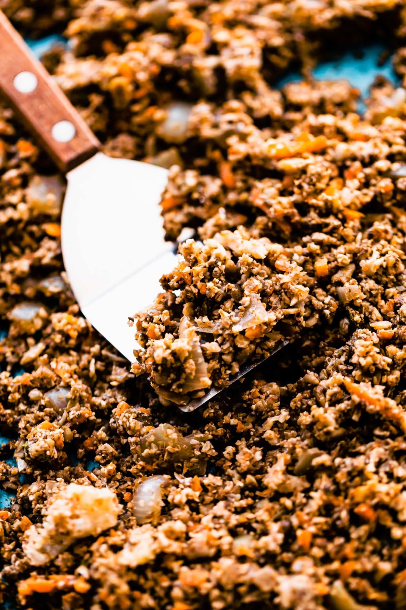 Photo of vegan taco meat being scooped with a spatula off a sheet pan.