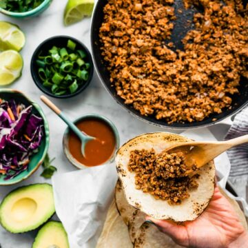 Overhead tabletop image of vegan tacos being prepared with vegan taco meat and fresh veggies.