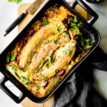 Overhead view breakfast lasagna in black baking dish topped with long slices platains.
