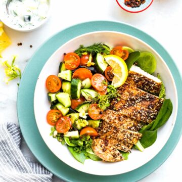 Overhead view turquoise rimmed bowl filled with Za'atar chicken and mixed greens and vegetables