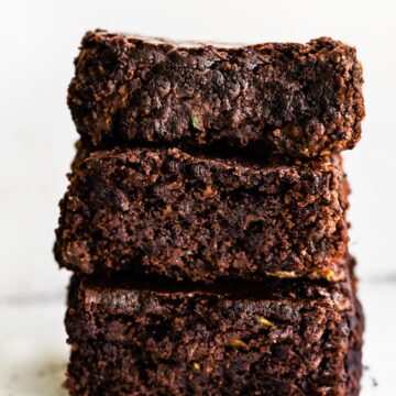 A stack of three zucchini brownies on a white countertop.